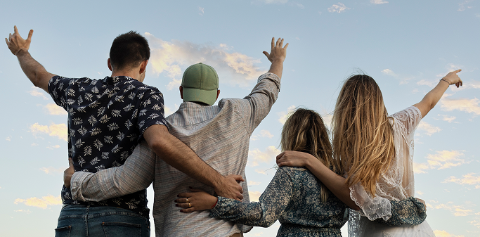 Friends embracing beach looking sky